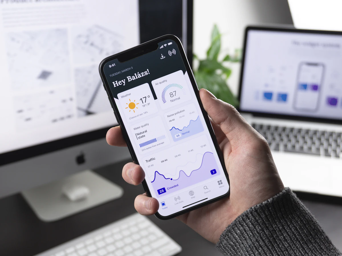 Hand holding a phone showing a weather app interface.