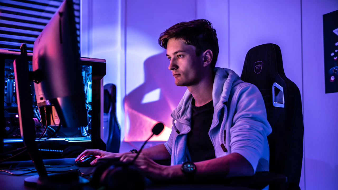 Gamer at a computer under purple light.